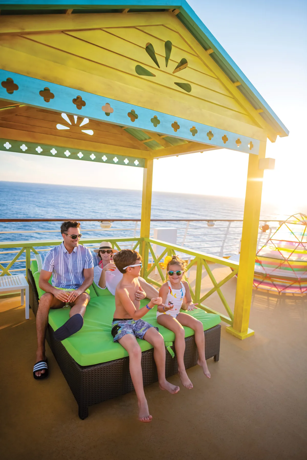 A family of four relaxing in a private cabana on deck at sunset